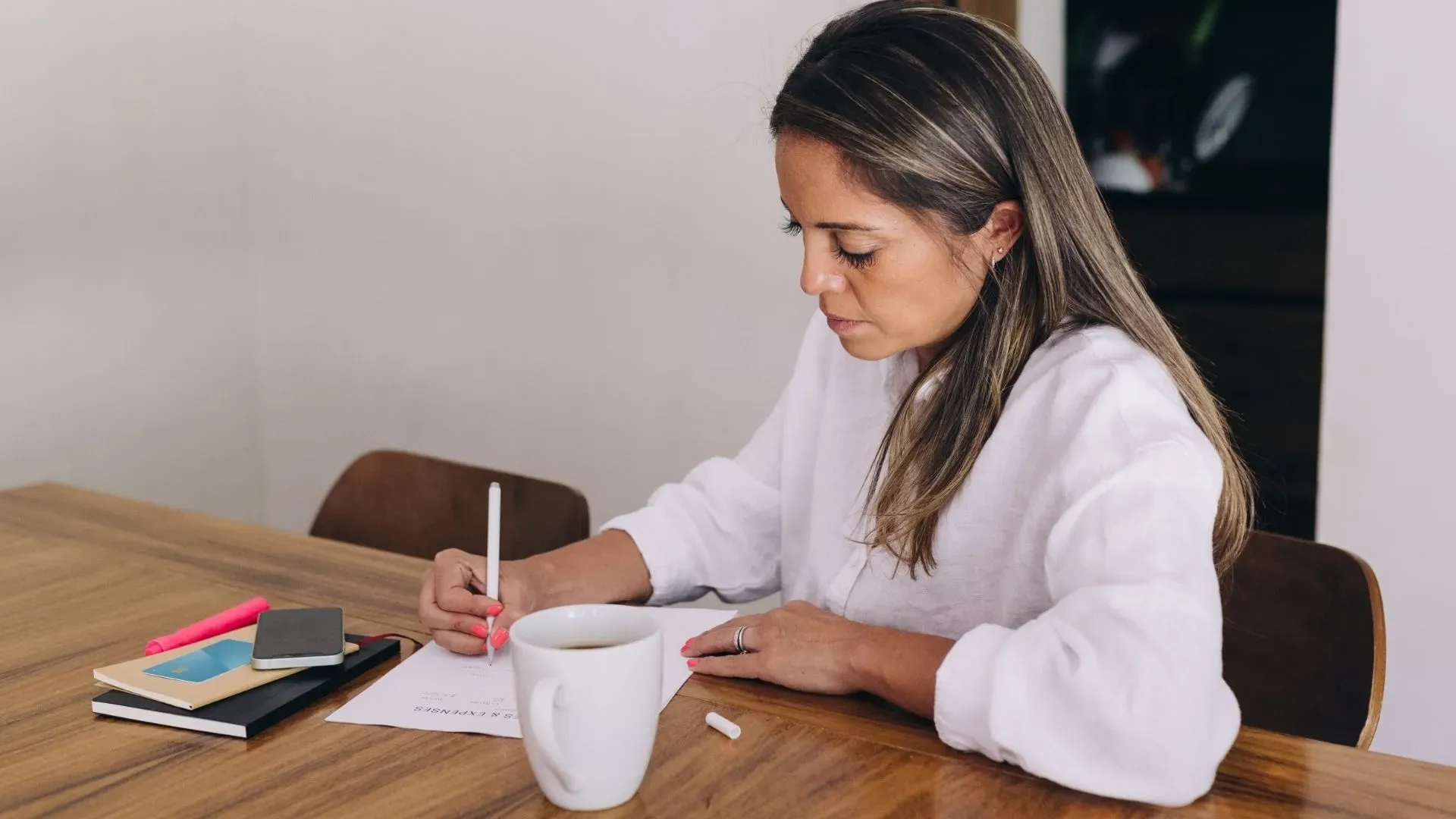 Femme entrepreneure planifiant sa rentrée avec un carnet et un café, pour préparer son business en septembre
